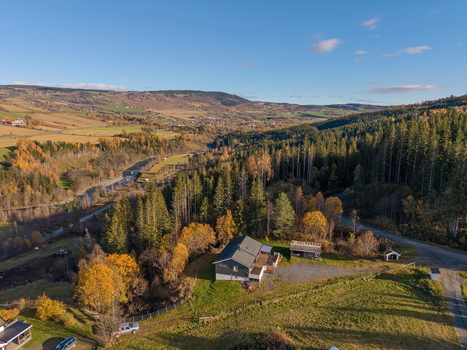 Enebolig med tilhørende garasje, omgitt av skog og åpent landskap. Landlig beliggenhet med utsikt mot åser og fjell. Galleribilde