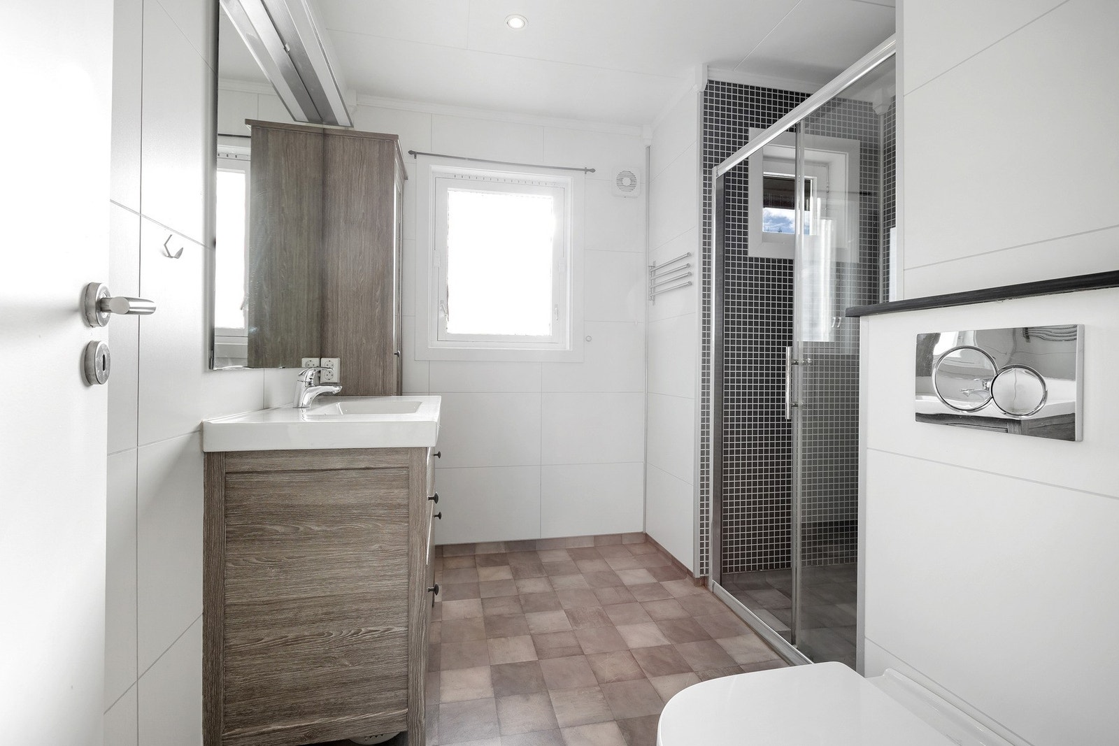 Bad med dusjkabinett, vindu, og moderne innredning. Lyse fliser på veggene og mørkere fliser på gulvet. Galleribilde