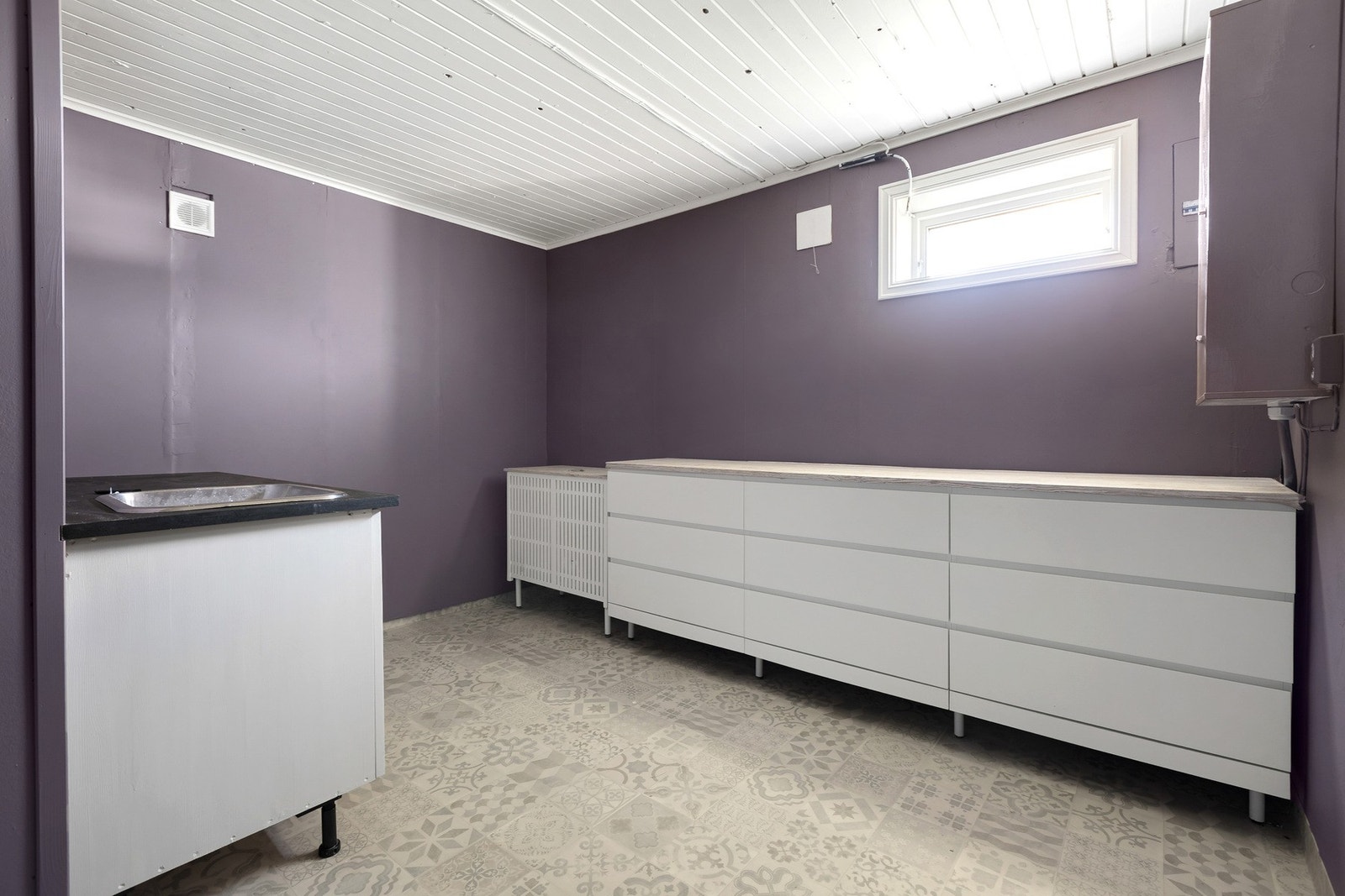 Vaskerom i kjelleretasjen har hvit innredning med skuffer og utslagsvask. Galleribilde