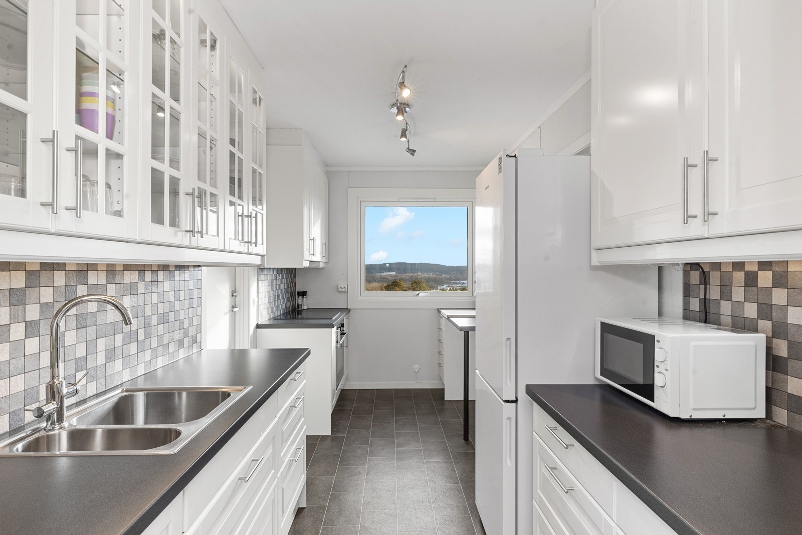 Hvit kjøkkeninnredning fra IKEA med integrert platetopp, stekeovn og oppvaskmaskin Galleribilde