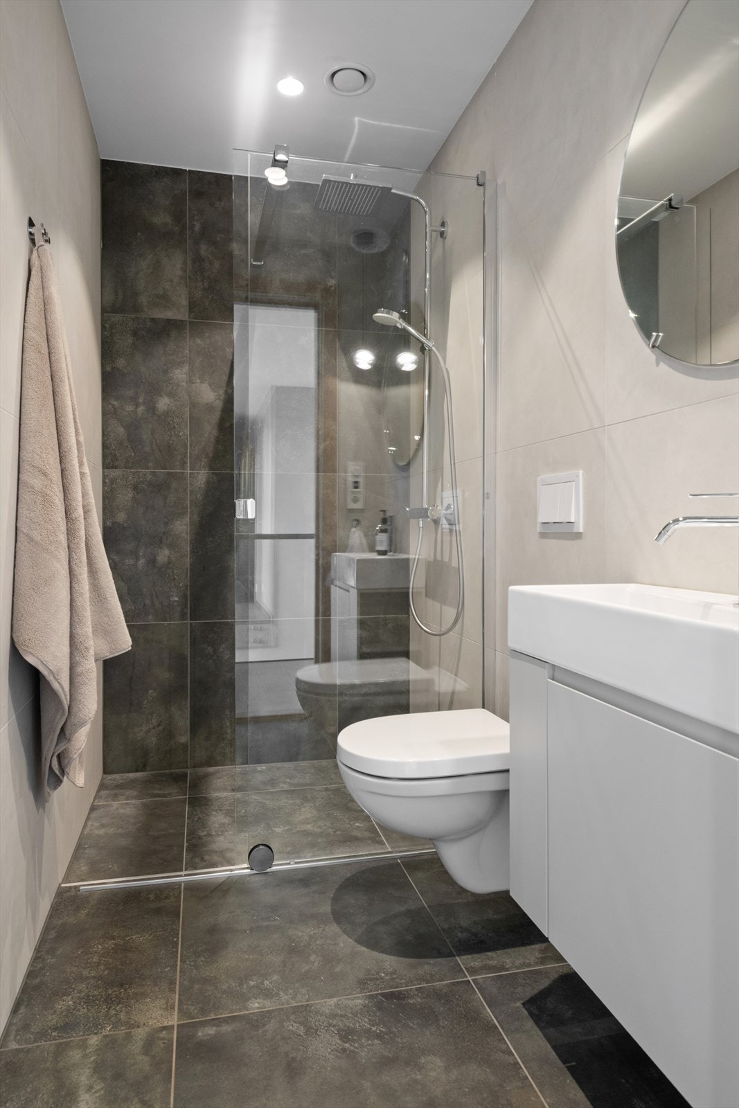 Badet har flislagte gulv og vegger, innredet med servant, vegghengt toalett og dusjhjørne. Galleribilde