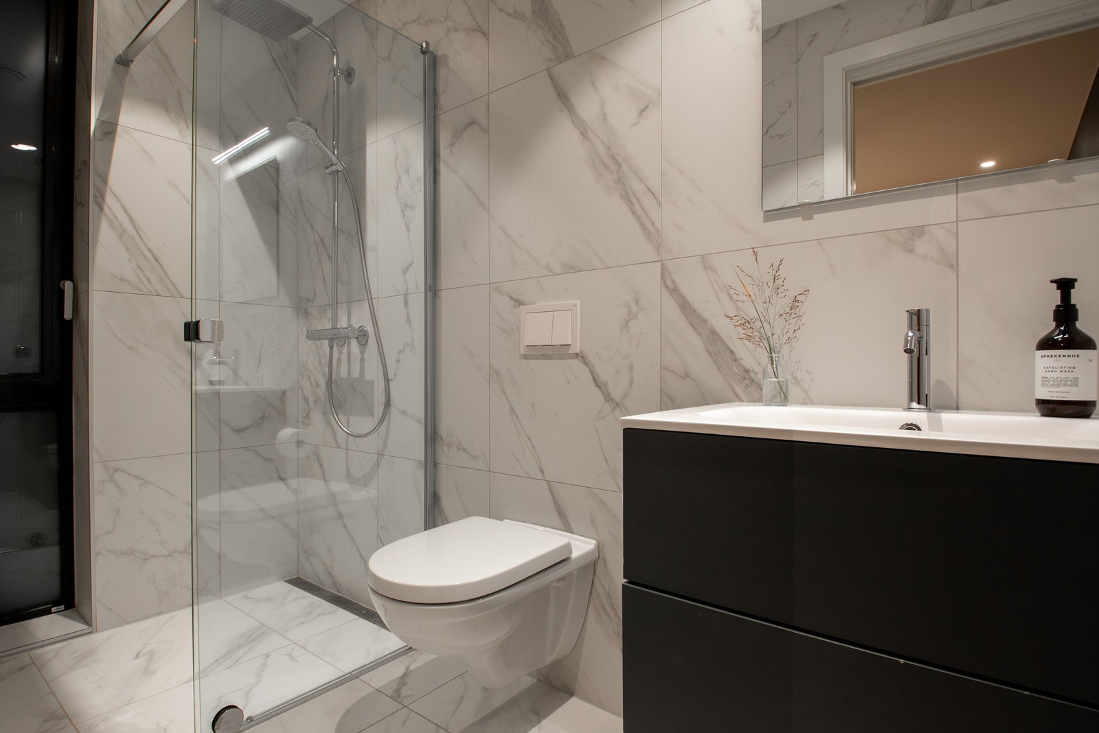 Badet har flislagte gulv og vegger, innredet med servant, vegghengt toalett og dusjhjørne. Galleribilde