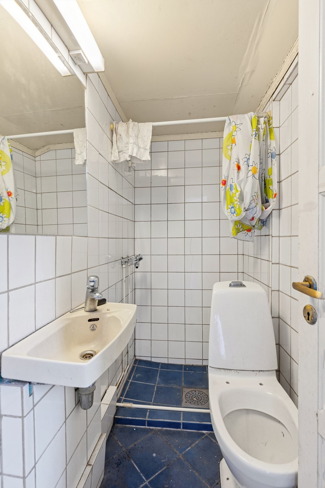 Badet er fra før 1997. Flislagte vegger og gulv. Innredet med servant, innmurt speil med belysning over, dusjnisje og gulvmontert toalett. Galleribilde