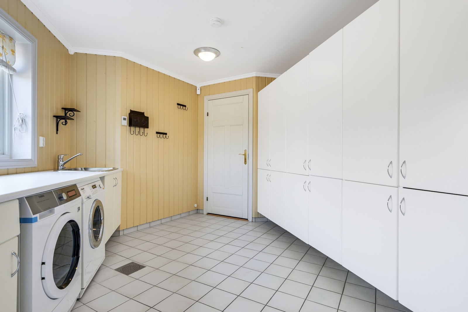 Vaskerommet er svært praktisk med opplegg for vaskemaskin og tørketrommel side by side Galleribilde