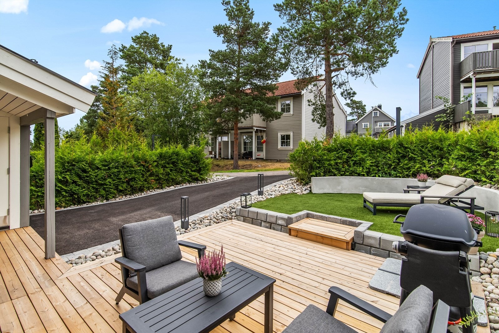 Busker og trær i bakgrunnen gir privatliv og en naturlig ramme rundt uteområdet. Galleribilde