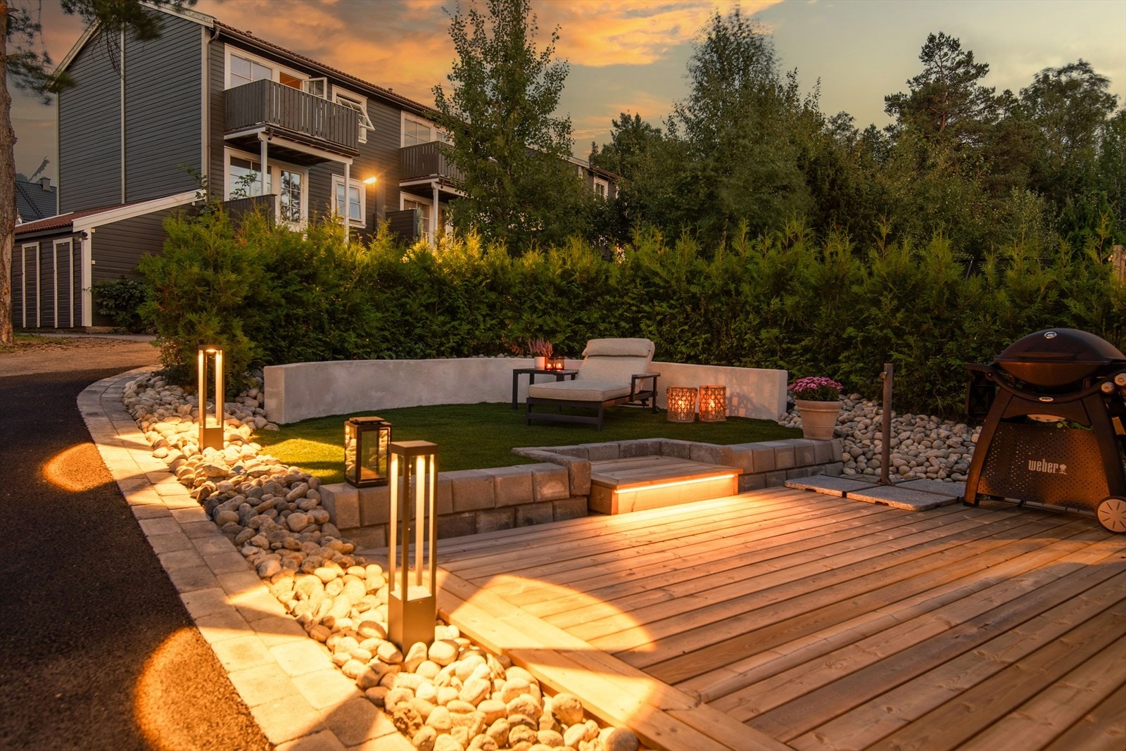 Terrassen er omkranset av dekorative steiner og moderne utebelysning som gir en varm og innbydende atmosfære. Galleribilde