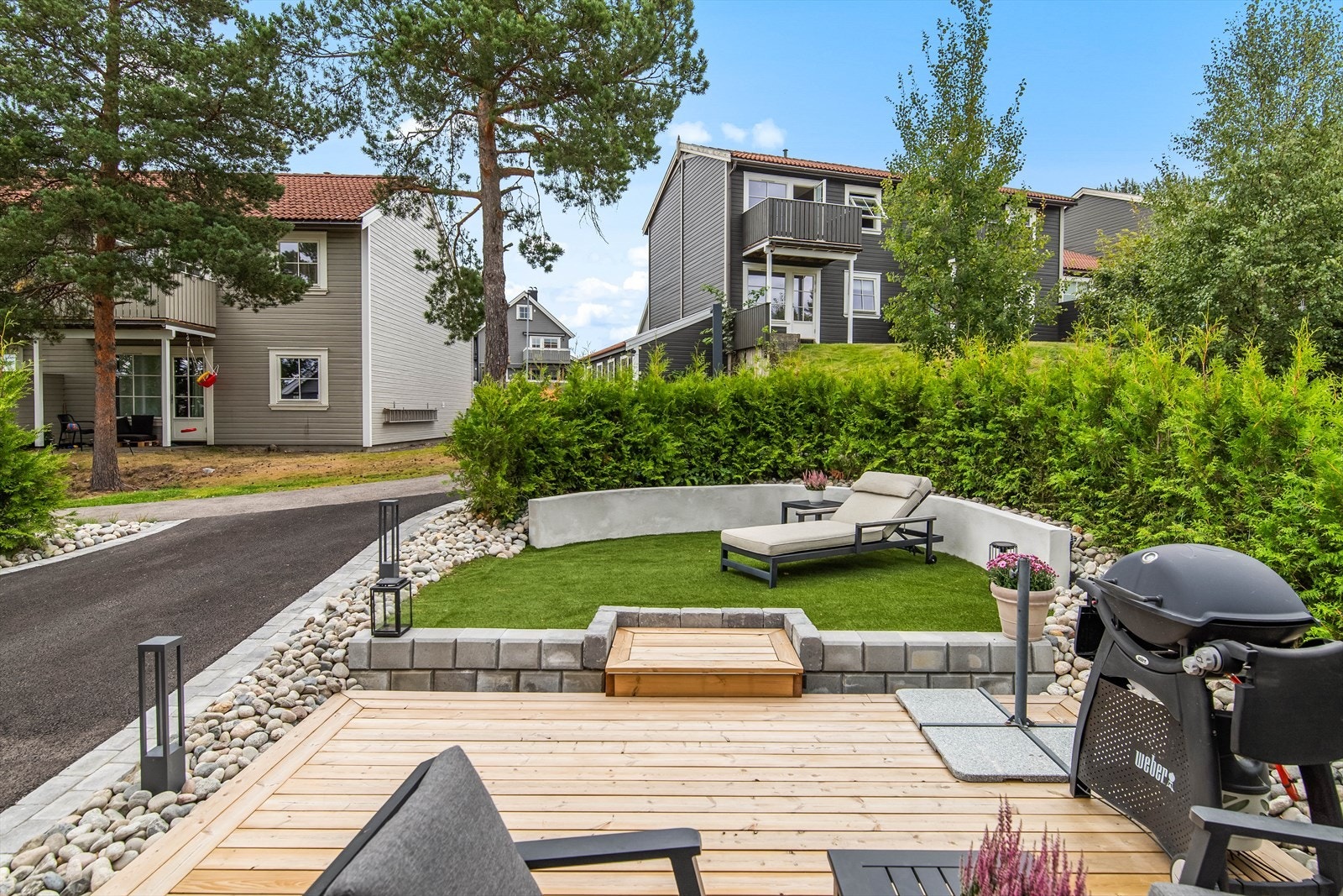 Foran terrassen ligger en liten, velstelt gressflekk med en lav, buet mur som fungerer som sitteplass. Galleribilde