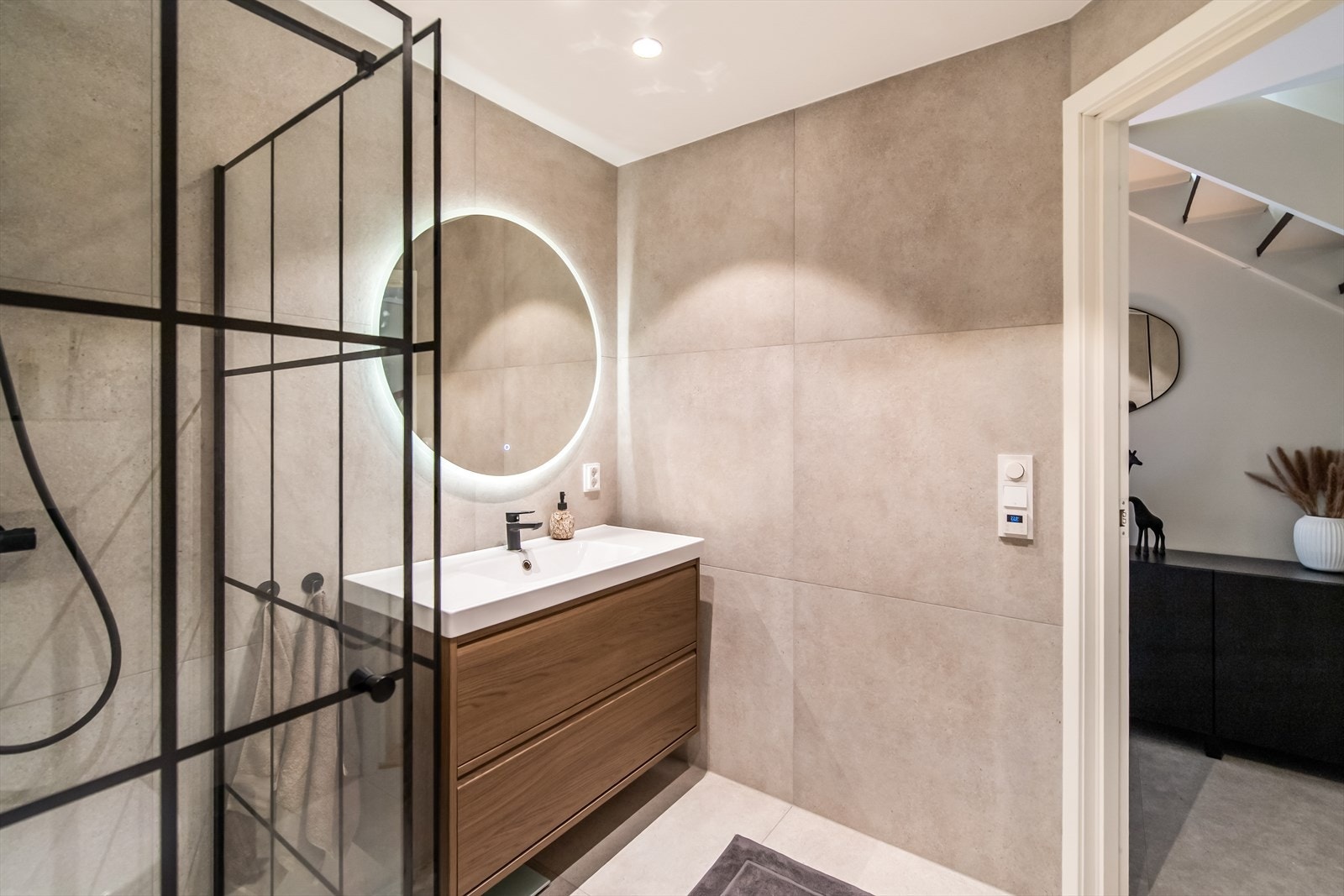 Dusjen er avgrenset med sorte, smale profiler i stål og klart glass - en populær industriell stil som gir badet et moderne og sofistikert uttrykk. Galleribilde