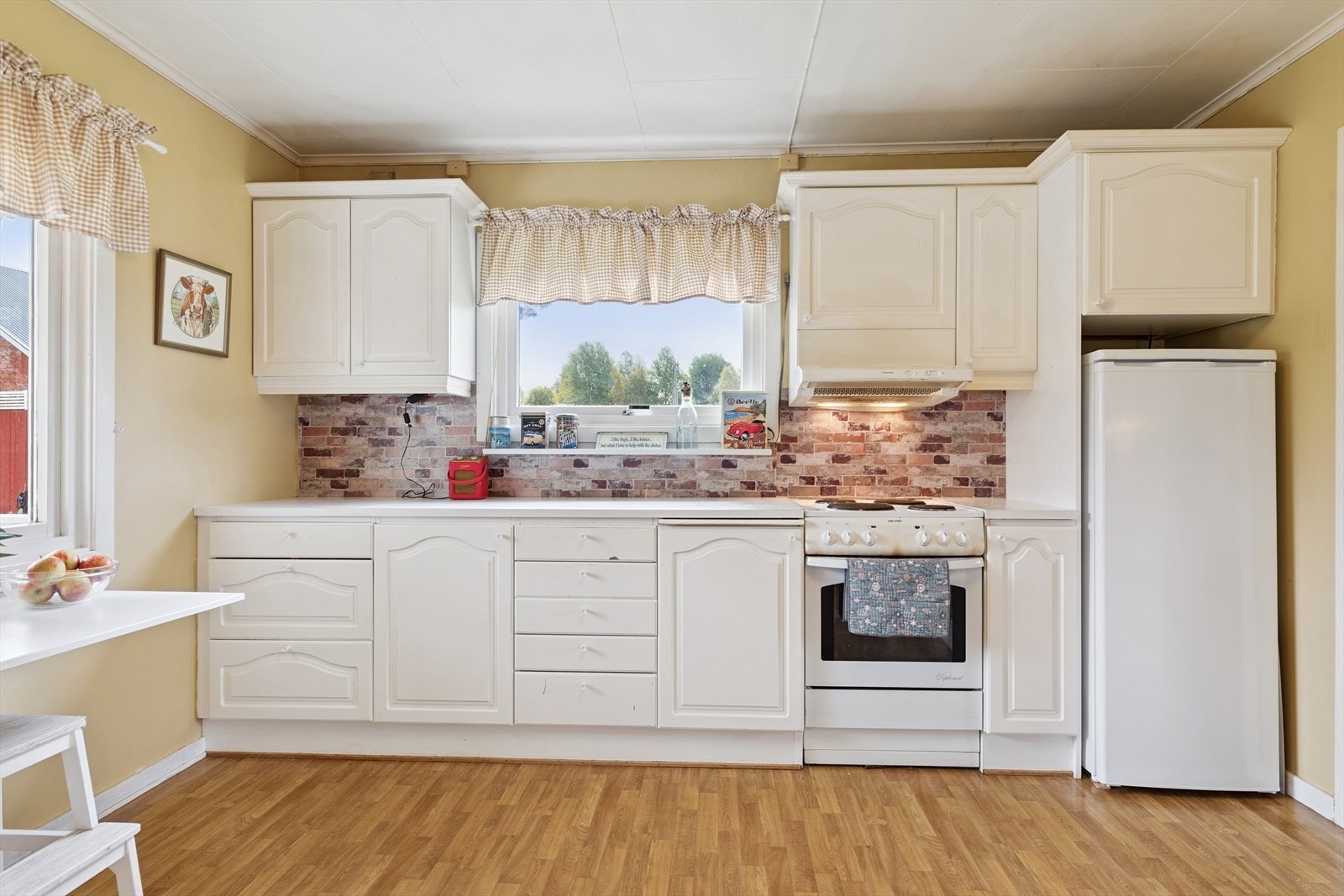 Kjøkkeninnredning med profilerte fronter og avsatt plass til komfyr og kjøleskap. Galleribilde