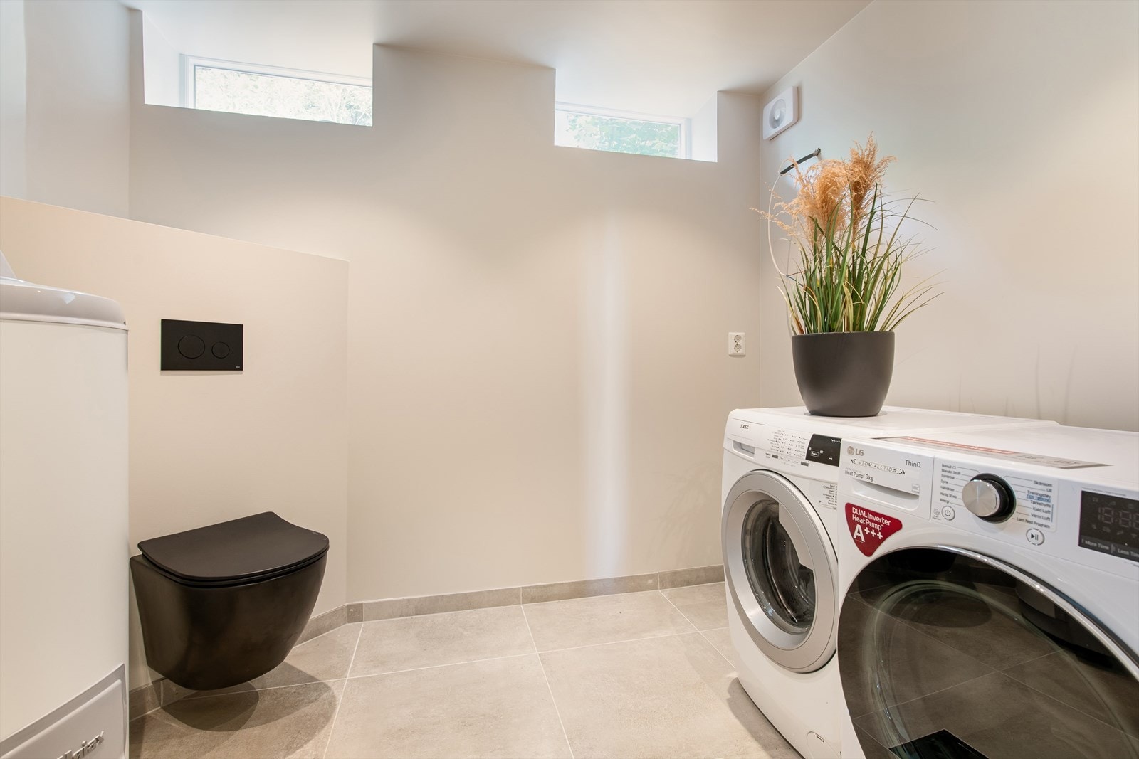 Vaskerom med belegg på gulv, tapetserte vegger og trepanel i innvendig tak. Rommet er utstyrt med toalett, utslagsvask og opplegg for vaskemaskin. Galleribilde