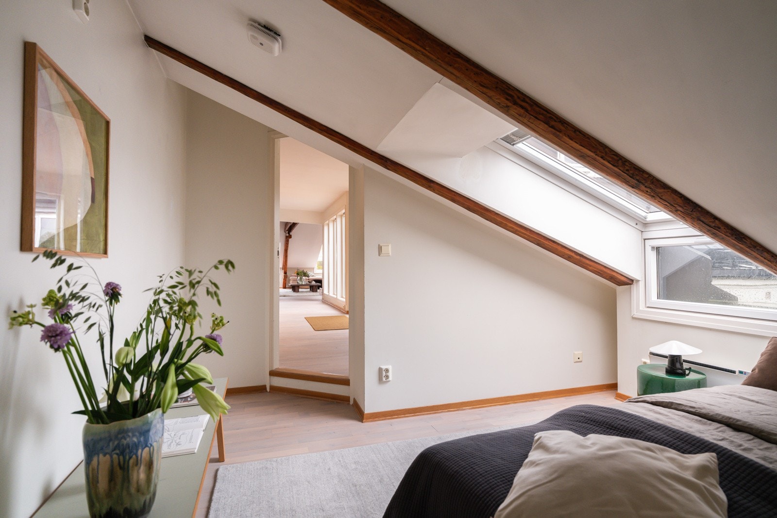 Også dette rommet har lys parkett på gulv, lysmalte overflater, synlige takbjelker og stort vindu som slipper inn fint lys. Fra soverommet har du rømningsvei ut til loft. Galleribilde