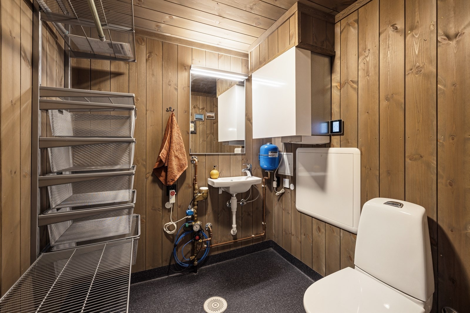 Teknisk rom har gulvbelegg, panel på vegg og i himlingen. Rommet er innredet med en enkel servant og gulvmontert toalett. Galleribilde