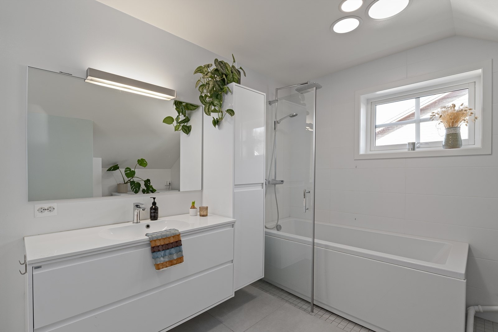 Badet har god belysning og inneholder dusj med badekar, servant med skuffeinnredning, høyskap, toalett og plass for vaskemaskin og tørketrommel. I tillegg er det tilkomst til teknisk bod/ekstra lagringsplass. Galleribilde