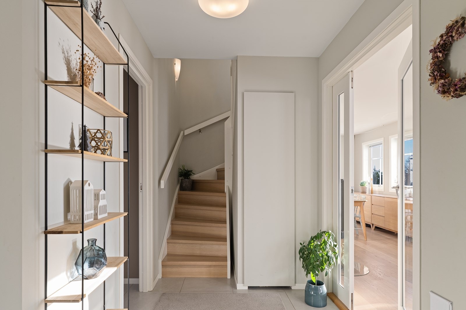 Romslig gang med fliser på gulv. Praktisk bod under trapp. Galleribilde