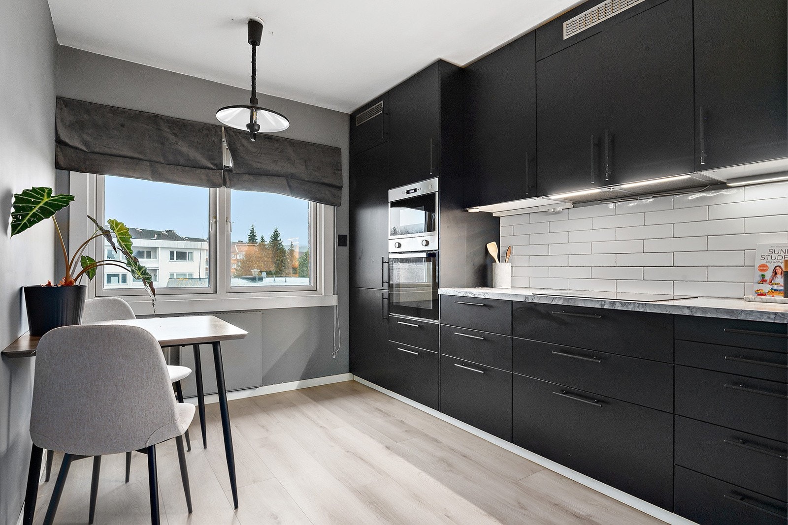 Innredningen er fra IKEA (2018) med glatte, folierte fronter og integrerte hvitevarer. Over kjøkkenbenken er det overskap med belysning under og ventilator med kullfilter. Galleribilde