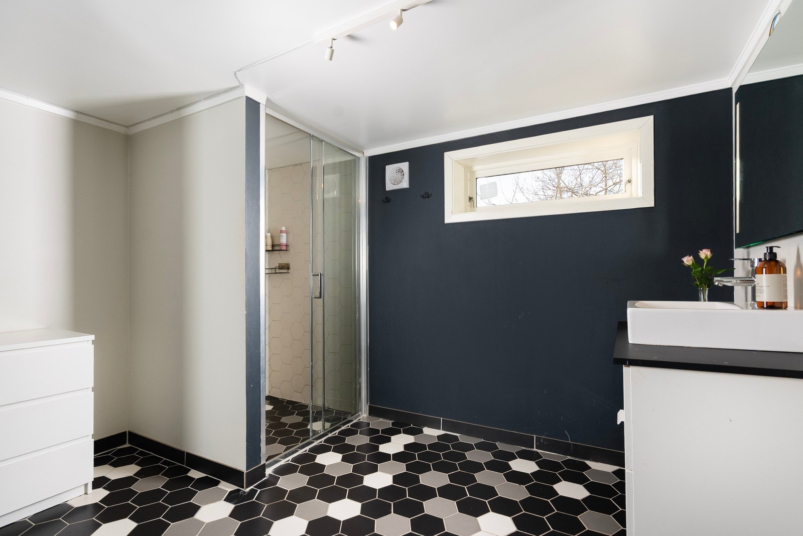 Et moderne bad/vaskerom med stilrene fliser og praktiske løsninger, inkludert ekstra dusjmuligheter for en enkel hverdag Galleribilde