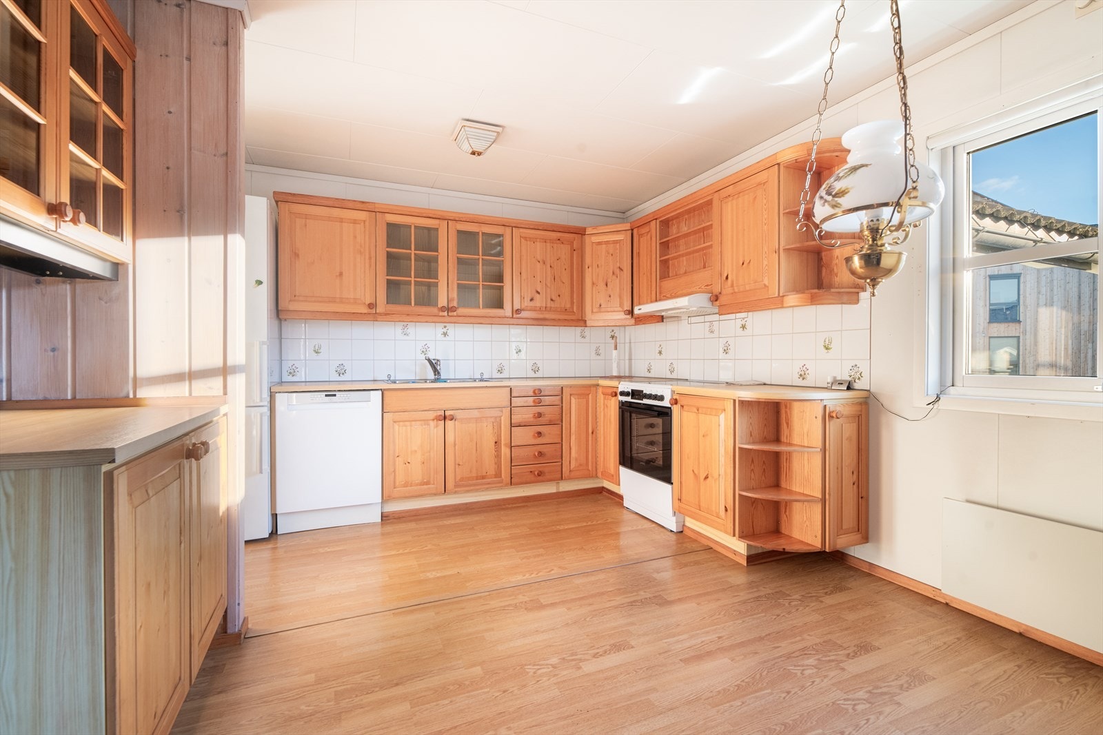 På kjøkkenet er det en koselig spiseplass ved vinduet. Her er det godt med oppbevaringsplass i innredning med profilerte fronter og innslag av glass-skap og åpne hyller. Galleribilde