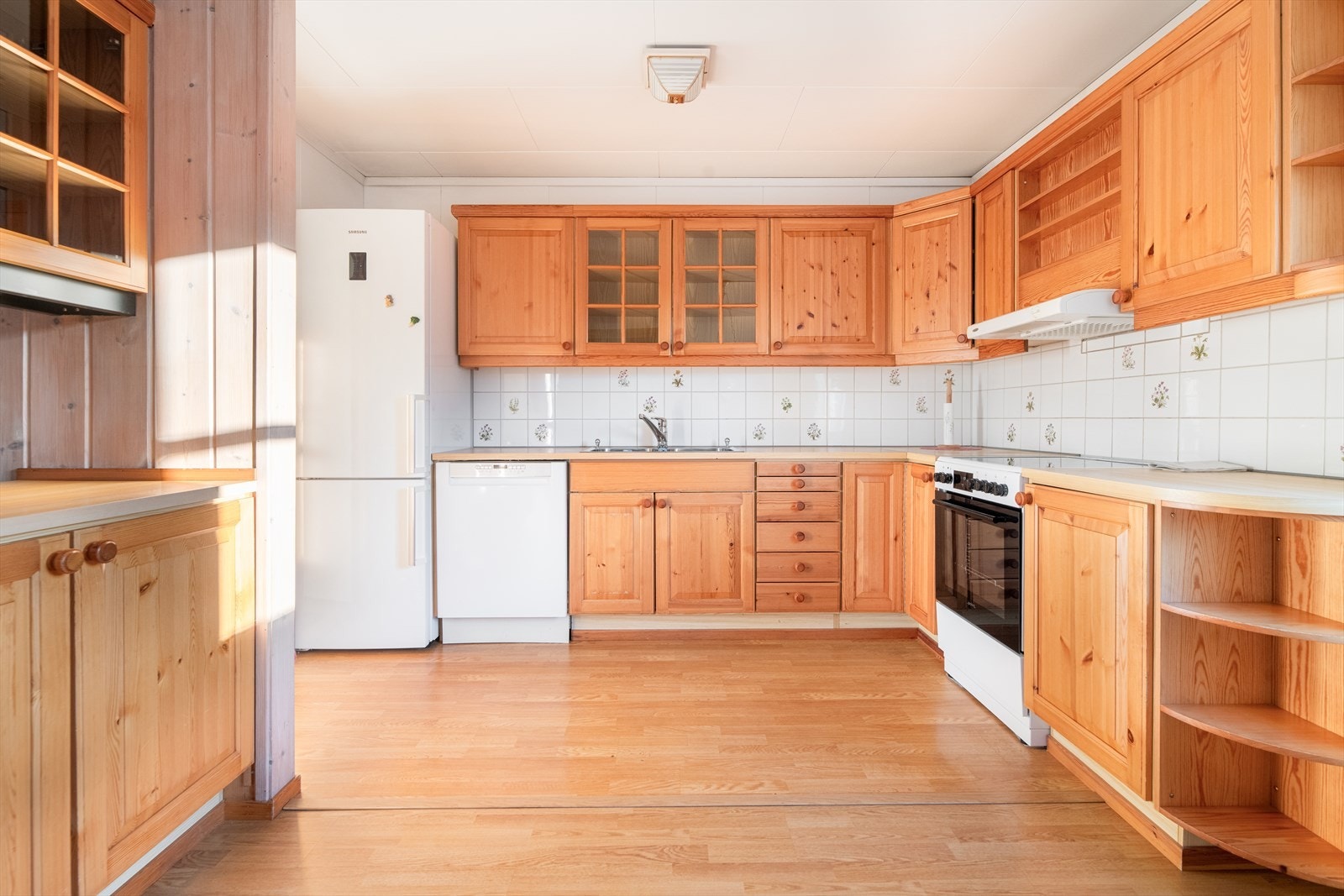 Gode arbeidsflater på laminerte benkeplater med flis på vegg. Kjøkkenet har avsatt plass til frittstående oppvaskmaskin, komfyr og kjøl/fryseskap som alle medfølger i salget. Galleribilde