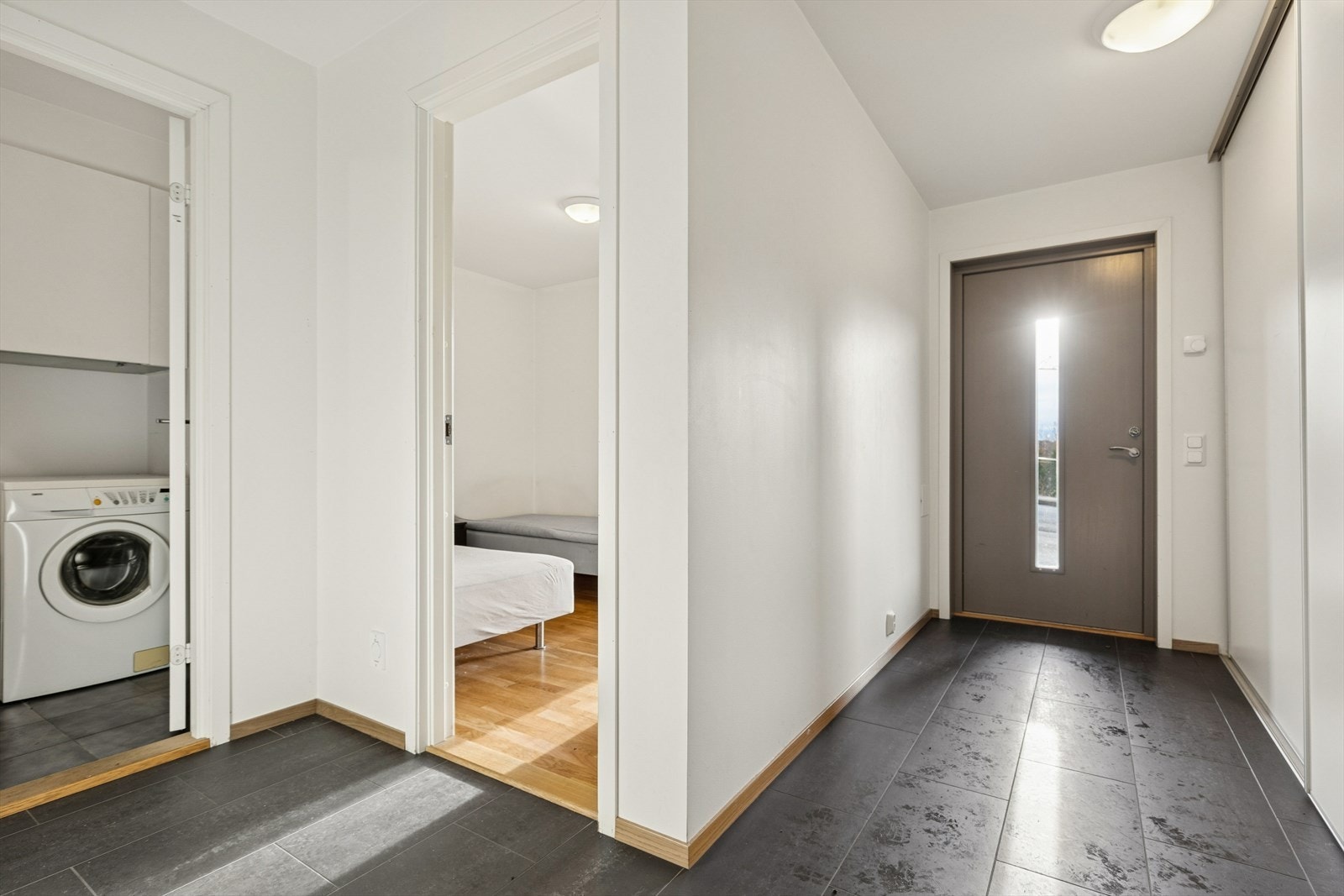 Entre/gang med fliser på gulv og stor skyvedørsgarderobe. Galleribilde