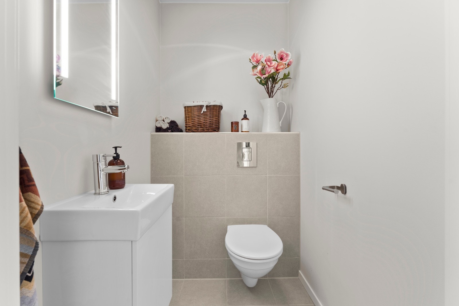 Toalettrommet har flislagt gulv og malte vegger, og er innredet med servant, speil med lys og vegghengt toalett. Galleribilde