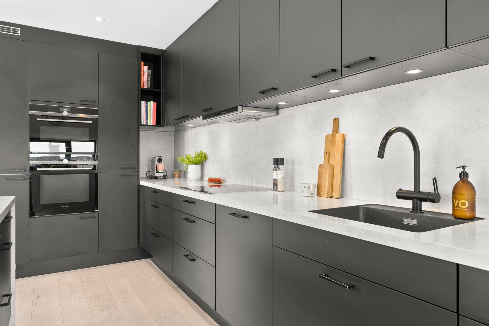 Stilrent og moderne Mobalpa kjøkken med sorte slette fronter og laminerte benkeplater med nedfelt oppvaskkum i kompositt. Galleribilde