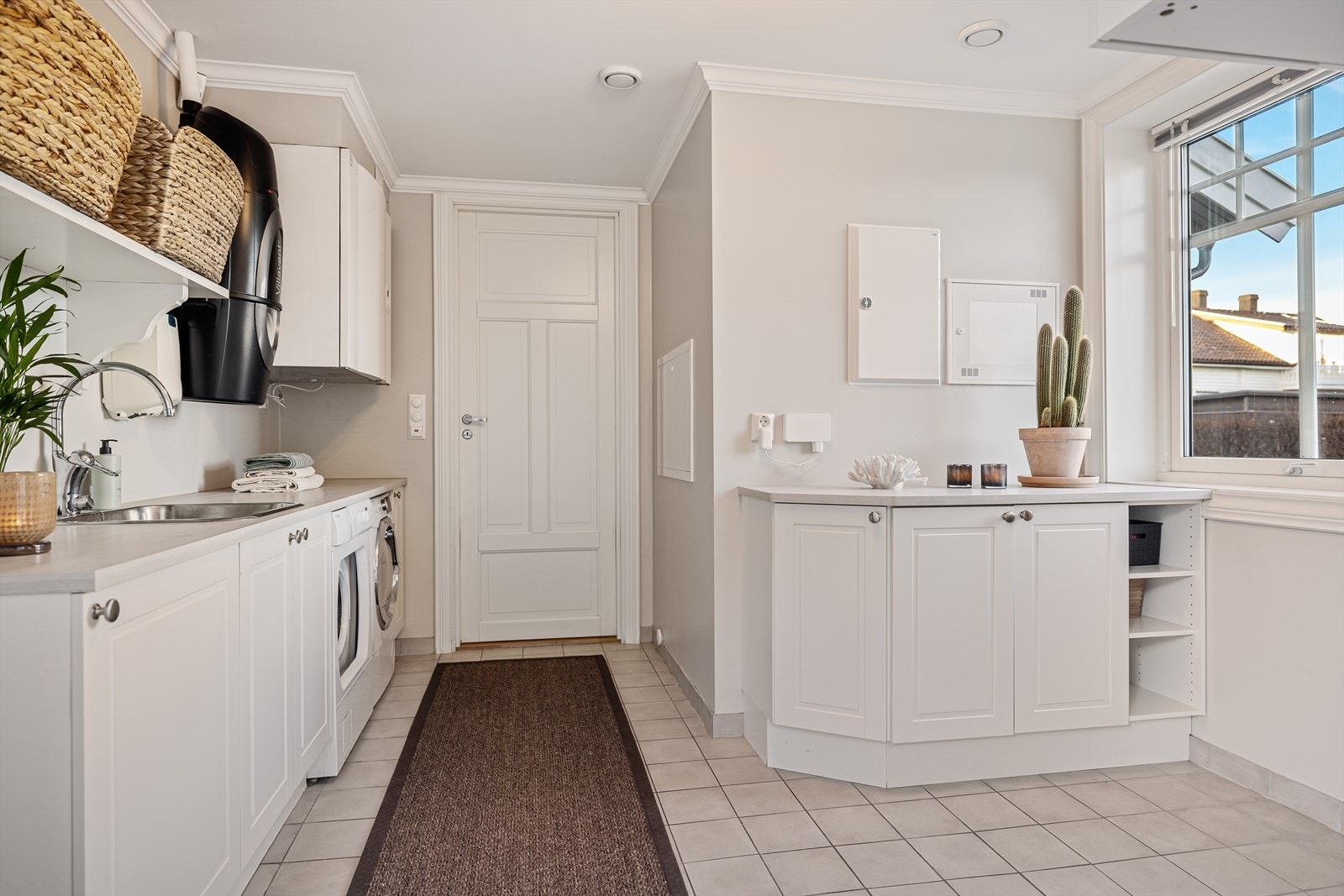 Vaskerommet er både lekkert og svært praktisk utformet - et funksjonelt rom som gjør hverdagen enklere. Her er det fliser på gulvet med behagelige, elektriske varmekabler, og veggene har malte plater som gir et rent, moderne uttrykk. Galleribilde