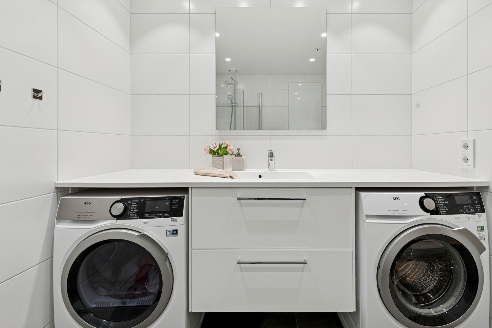 Badet har opplegg både til vaskemaskin og tørketrommel i smart løsning på hver sin side av servant. Galleribilde