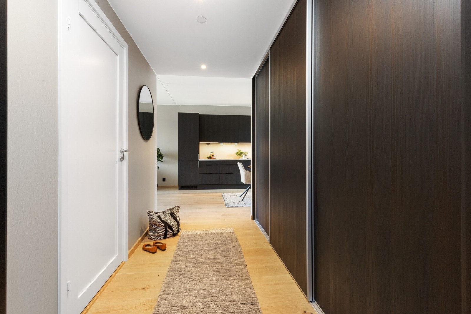 Entreen gir et luftig, pent førsteinntrykk av leiligheten og er smakfullt med bla. hvitpigmentert enstavs eikeparkett med gulvvarme, downlights i tak og en stor skyvedørsgarderobe som strekker seg hele veien inn mot stue og kjøkken. Galleribilde