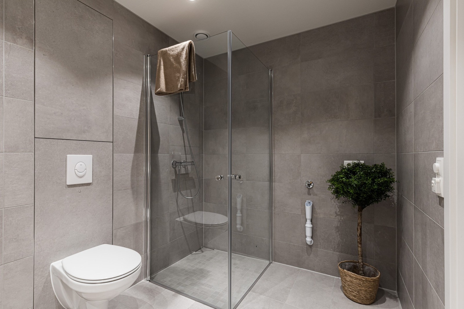 Badet har vegghengt toalett med softclose og et dusjhjørne med glassdører. Galleribilde