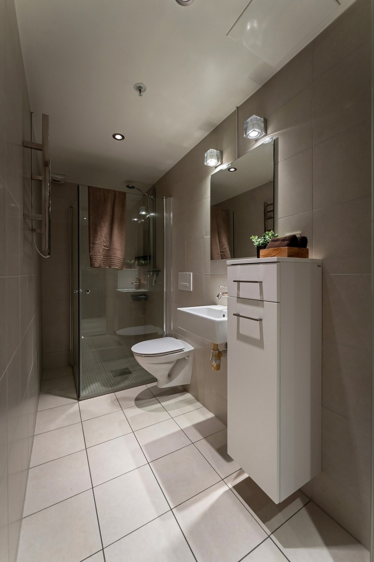 Det andre badet har lysbeige fliser på gulv og vegger, matchende mosaikk på gulvet i dusjen, downlights og gulvvarme. Galleribilde