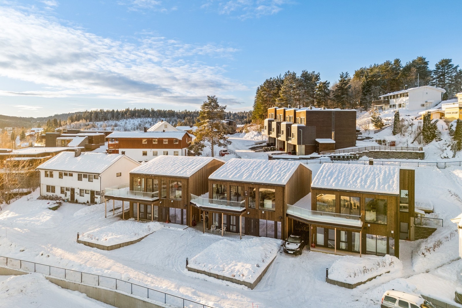 Velordnet privat utomhusareal med støttemurer, plen, terrasse, hekk, belysning, god parkeringsplass og romslig carport med ladepunkt for elbil. Galleribilde
