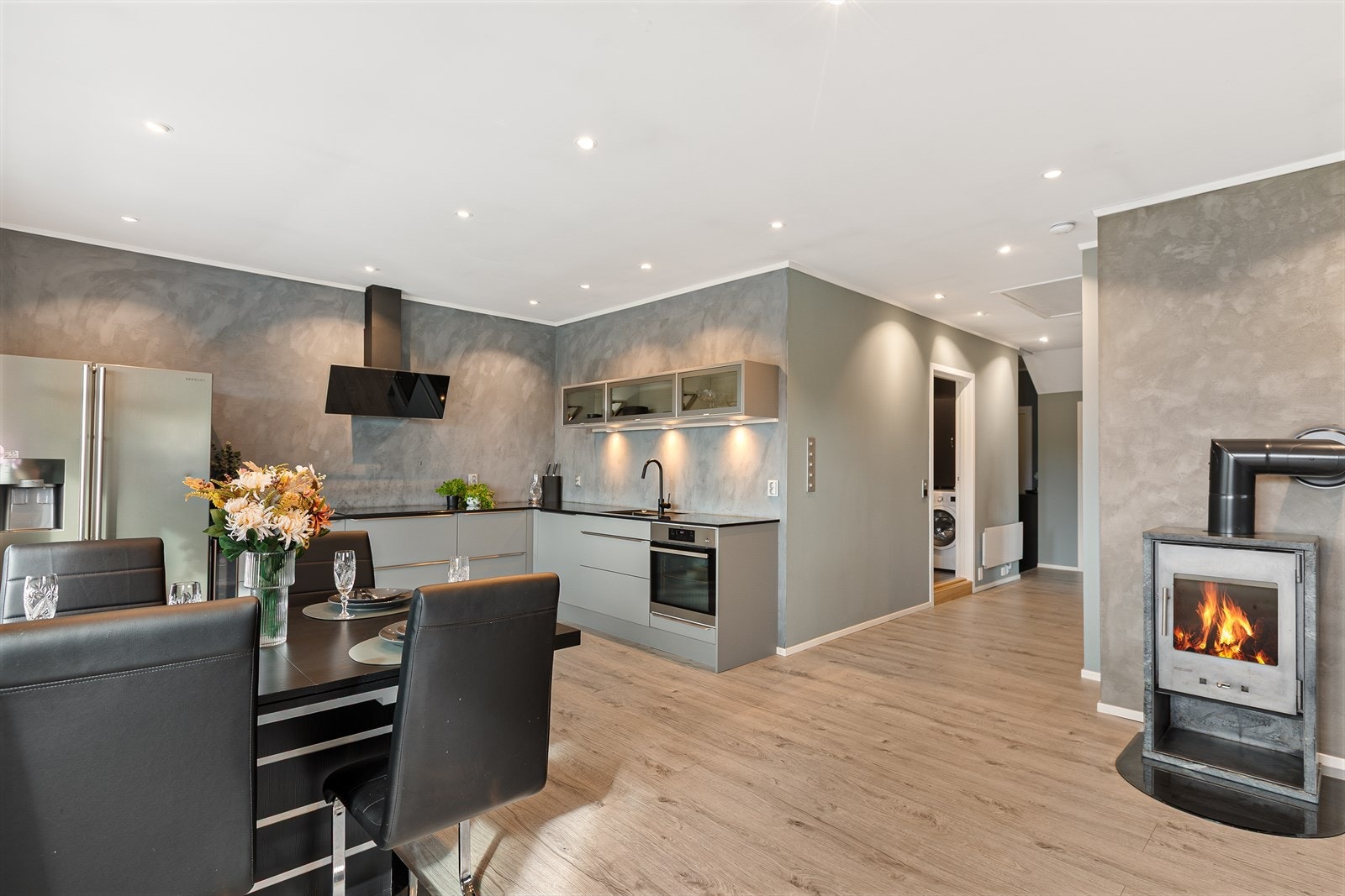 Den åpne løsningen binder spiseplassen sammen med kjøkkenet, og vedovnen gir både varme og atmosfære. Galleribilde