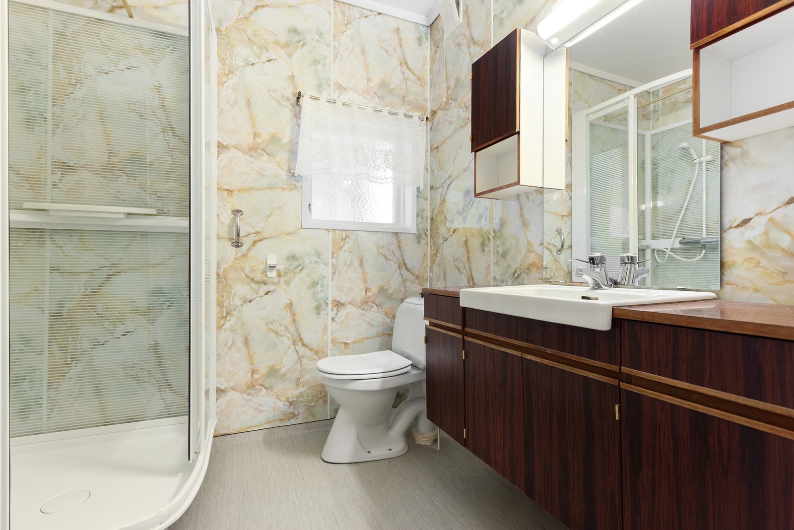 Eldre bad som er innredet med toalett, baderomsinnredning med servant , dusjkabinett og opplegg for vaskemaskin. Galleribilde