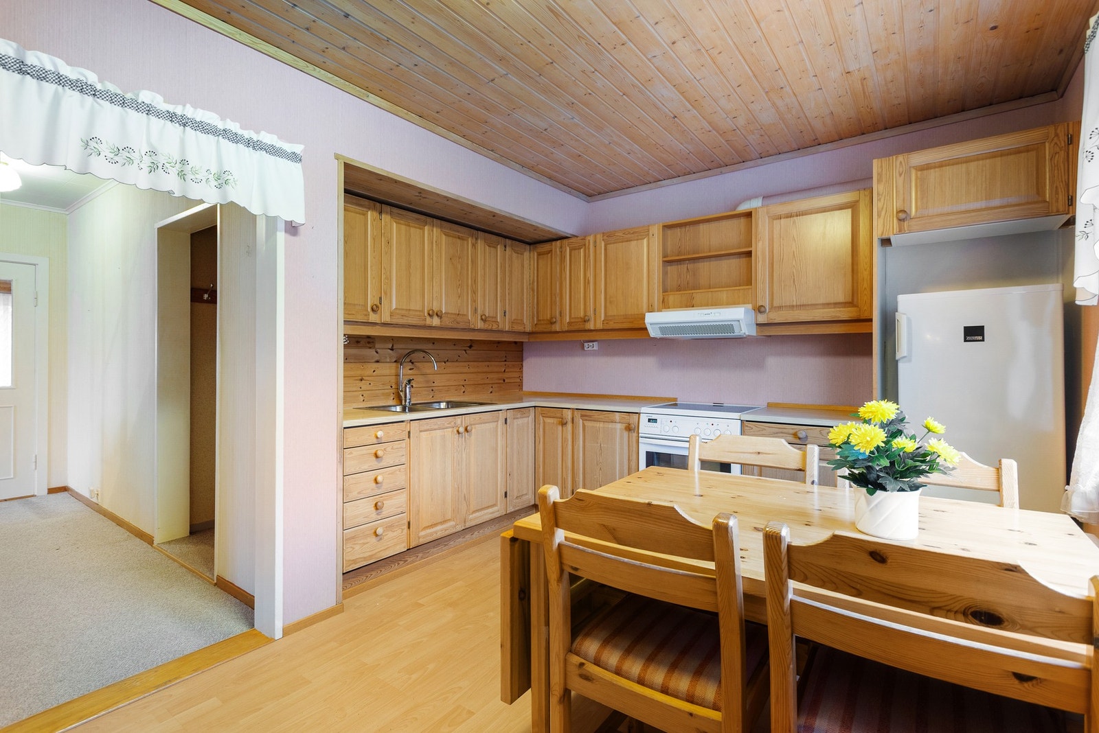 Kjøkkenet har en eldre innredning med furu dør-og skuffefronter og benkeplate i laminat Galleribilde