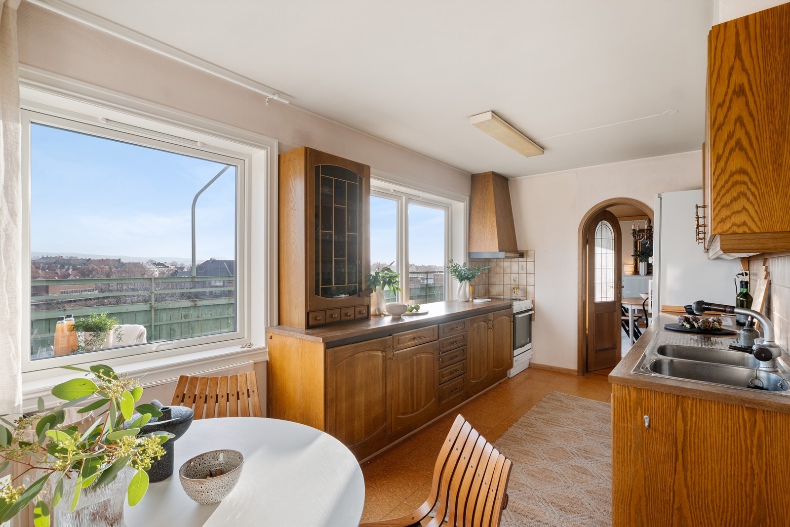 Separat kjøkken med eldre innredning og laminatfliser på gulvet. Her er det store vindusflater som gir godt med dagslys. Galleribilde