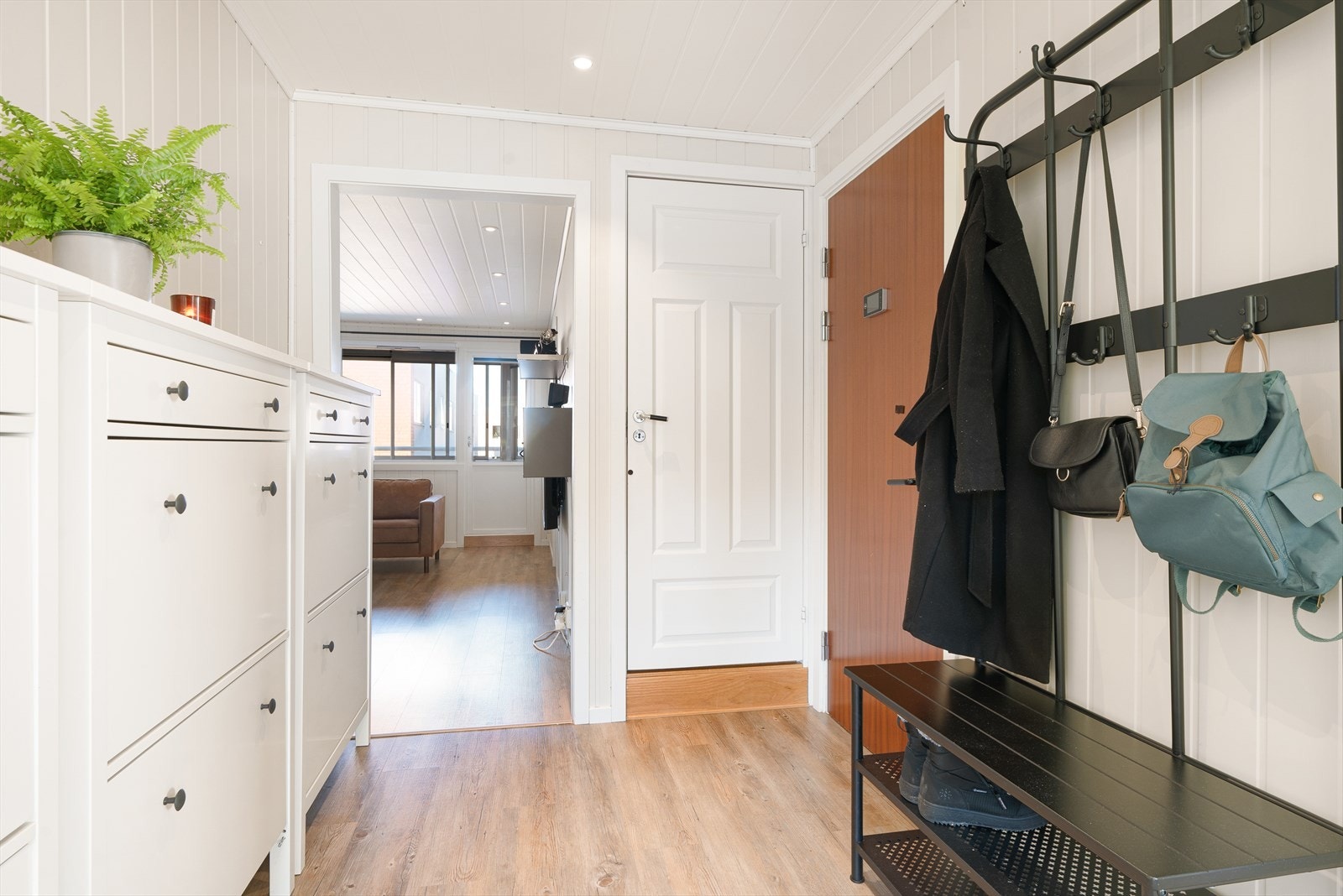 Velkommen inn! Lys entré med lysmalte panelplater og rikelig med oppbevaring for sko og yttertøy. Det er gjennomgående downlightsbelysning i himling i leiligheten. Galleribilde