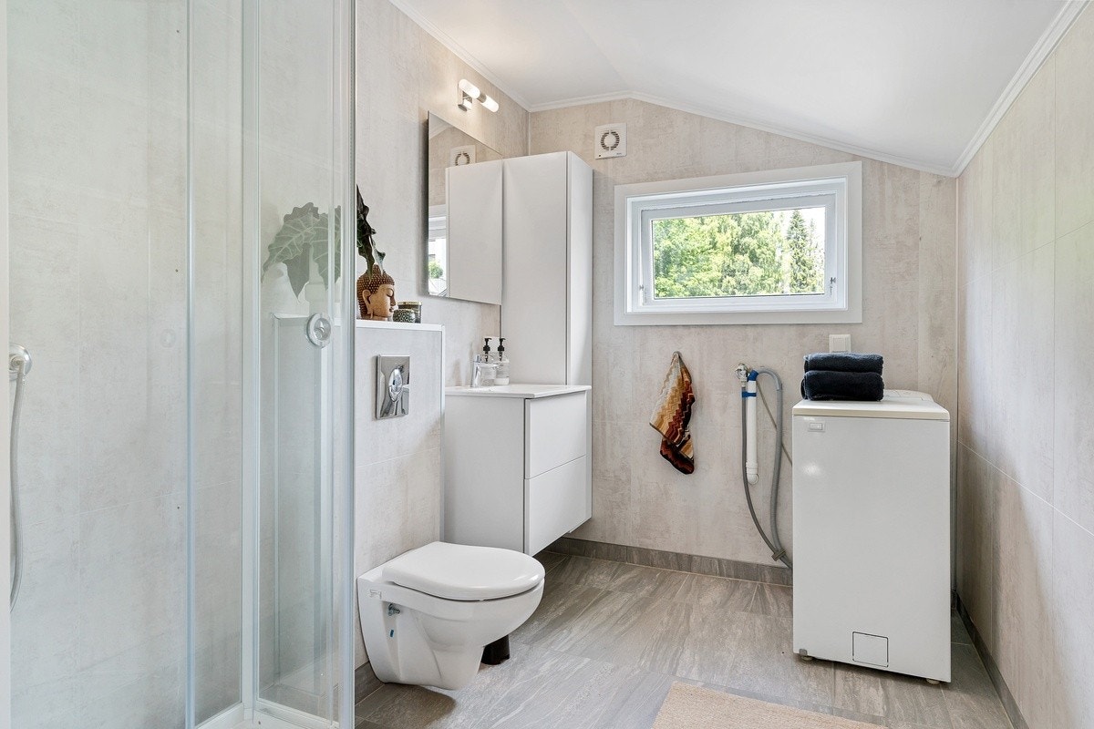 Badet har delikate farger og har både dusjkabinett og vaskemaskin. Galleribilde