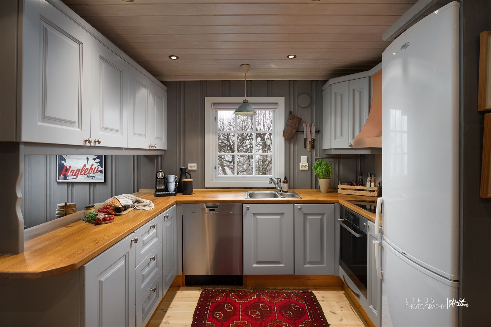 Profilerte kjøkkenfronter og benkeflate i heltre. Integrert induksjonstopp og stekeovn. Opplegg til oppvaskmaskin. Galleribilde