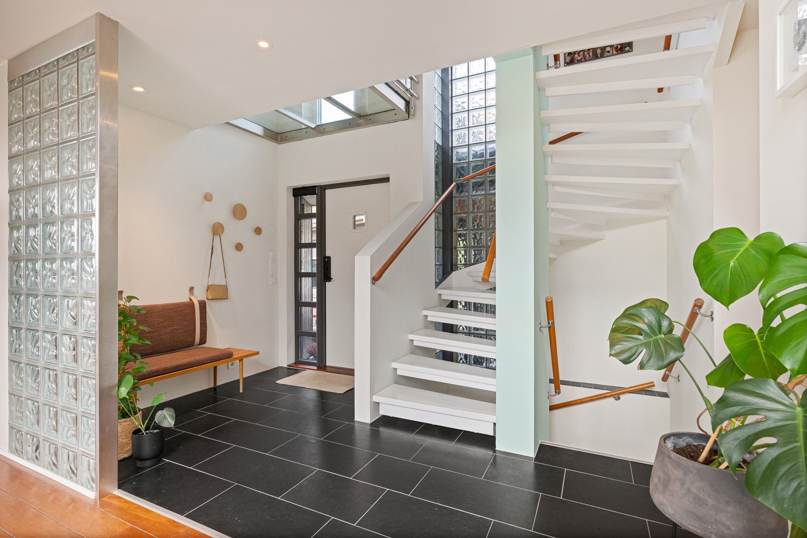 Romslig hovedinngang/hall, som også binder villaens 3 plan sammen. Her er det god garderobeplass og adkomst til et praktisk plassert gjestetoalett. Romfølelsen forsterkes av godt lysinnslipp via vindu og delvis glasstak mot etasjen over. Galleribilde