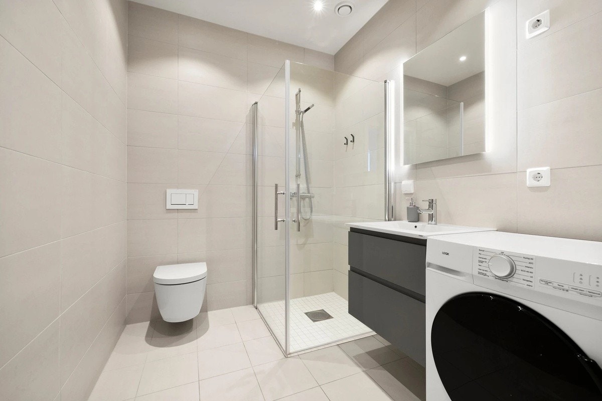 Lekkert baderom med vegghengt toalett, dusjhjørne med glassdører og moderne innredning. Galleribilde