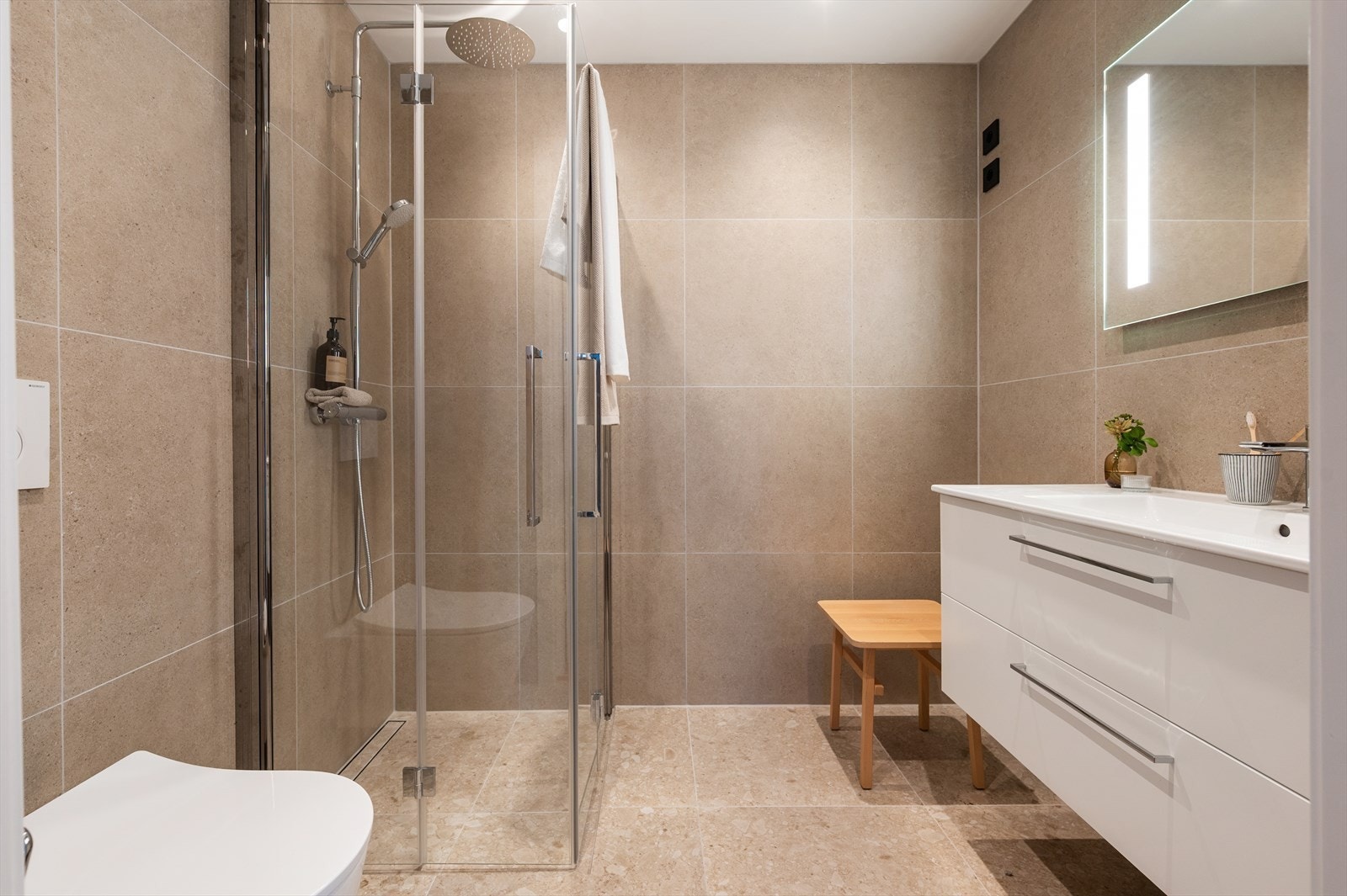 Et moderne og tidsriktig bad med store fliser i Pro Flodsten Earth på gulv og Pro Kalksten Earth på vegger. Galleribilde