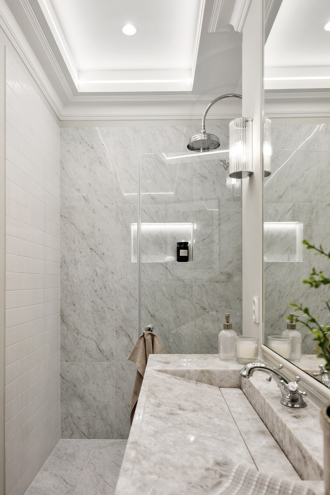 Taket er utført med nedtrukket himling og belysning. De detaljerte listene og den gjennomførte innrammingen løfter helhetsinntrykket og tilfører badet et eksklusivt preg. Galleribilde