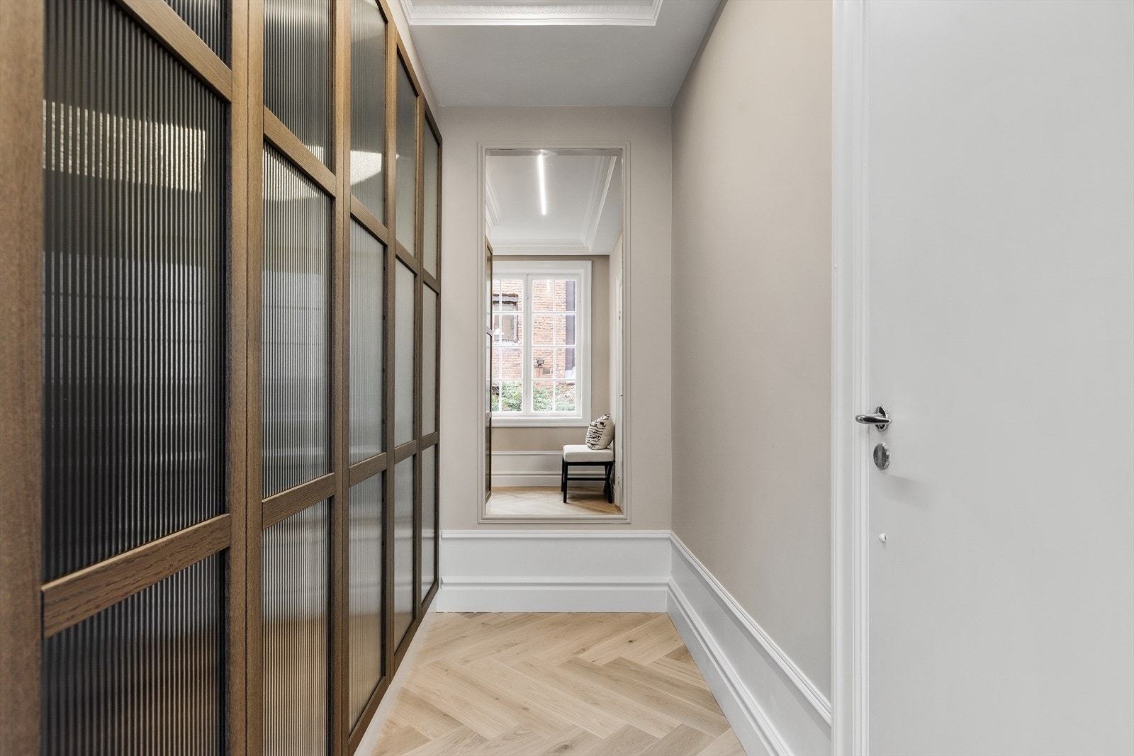 Walk-in-garderoben tilknyttet hovedsoverommet er innredet med plassbygde skap med mørke trefronter og rillet glass. Galleribilde