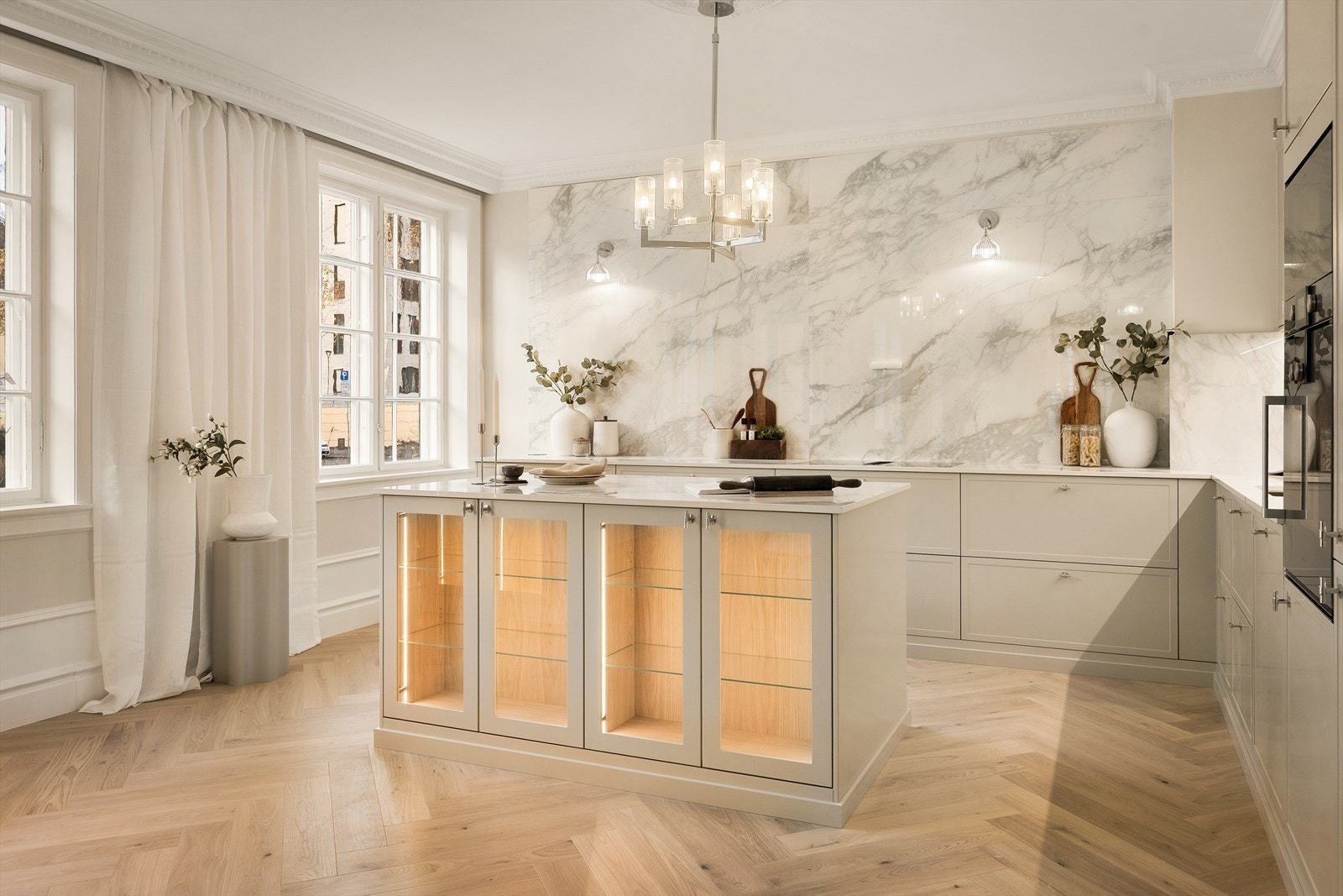 De innfelte vitrinedørene med integrert belysning tilfører varme og dybde, og gjør øya til et naturlig samlingspunkt i rommet. Galleribilde