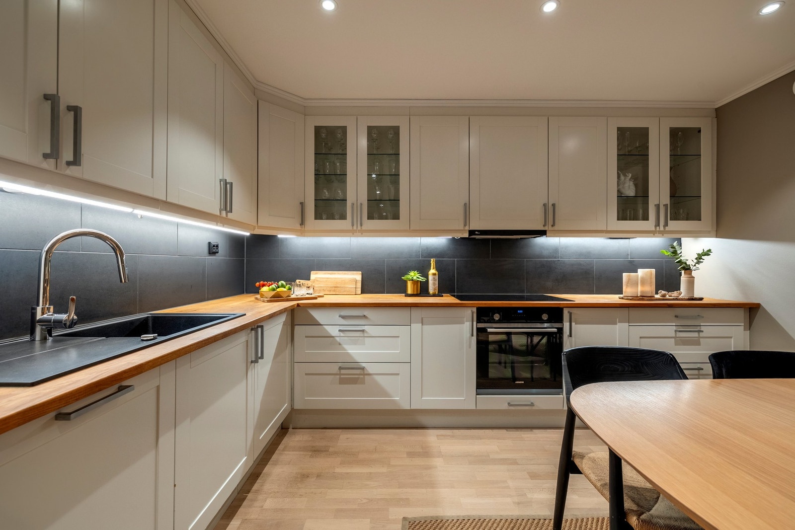 et er praktisk belysning over benken og fliser på vegg mellom overskap og kjøkkenbenk som gir et stilfullt preg. Galleribilde