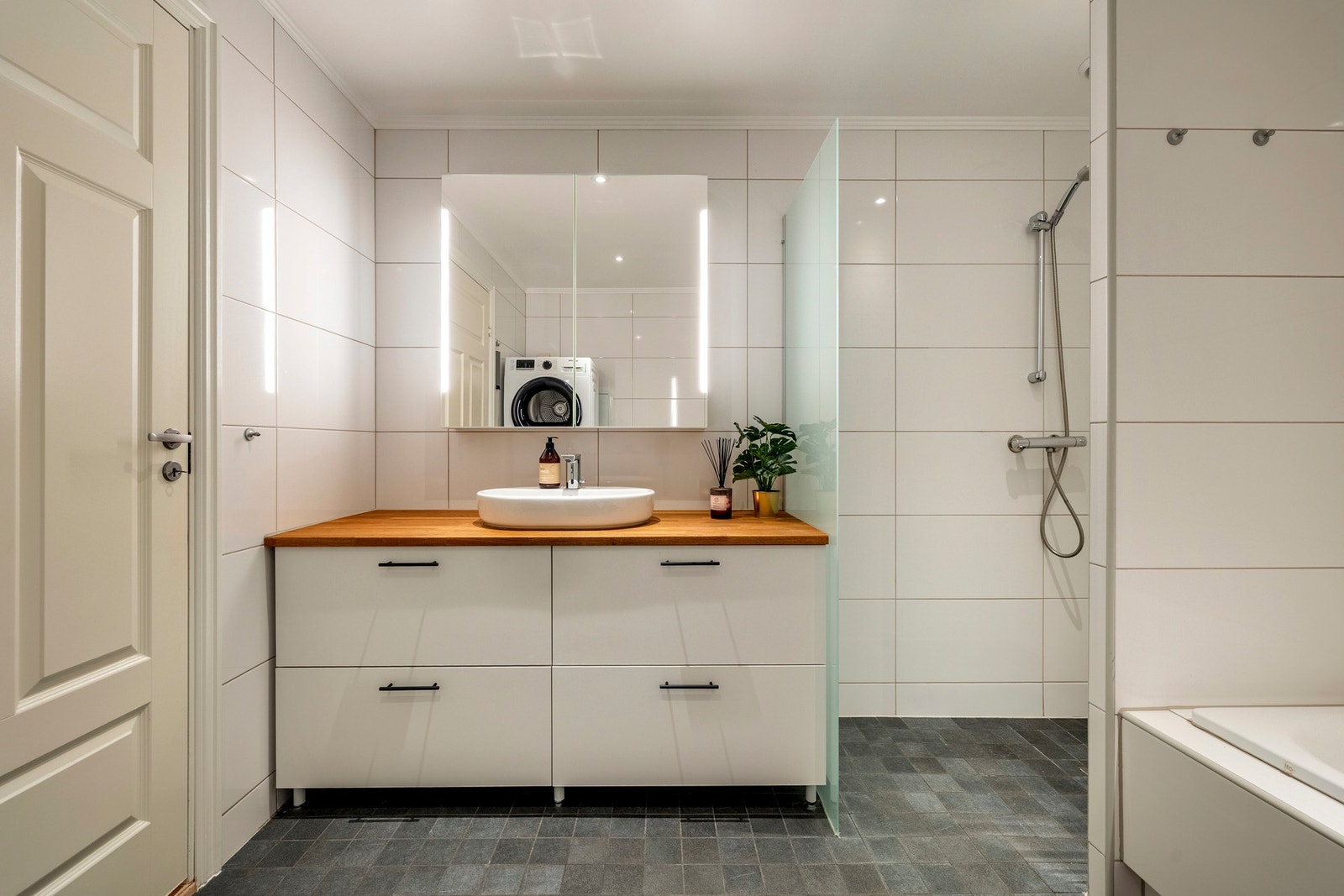 Innredningen består av servantinnredning, speil med lys i fronter på overskap over servant, toalett, innmurt badekar og skjermet dusjhjørne. Galleribilde