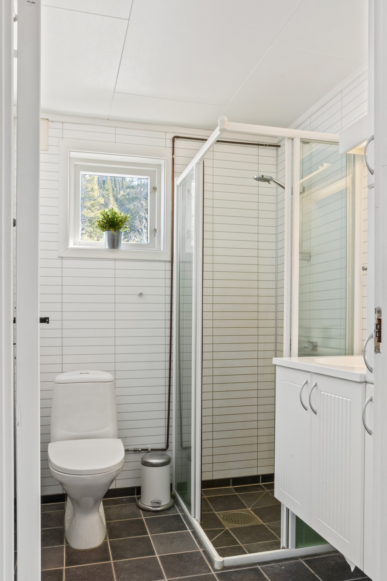 Pent bad som er innredet med helstøpt servantplate, klosett og dusjhjørne med skyvedører. Galleribilde