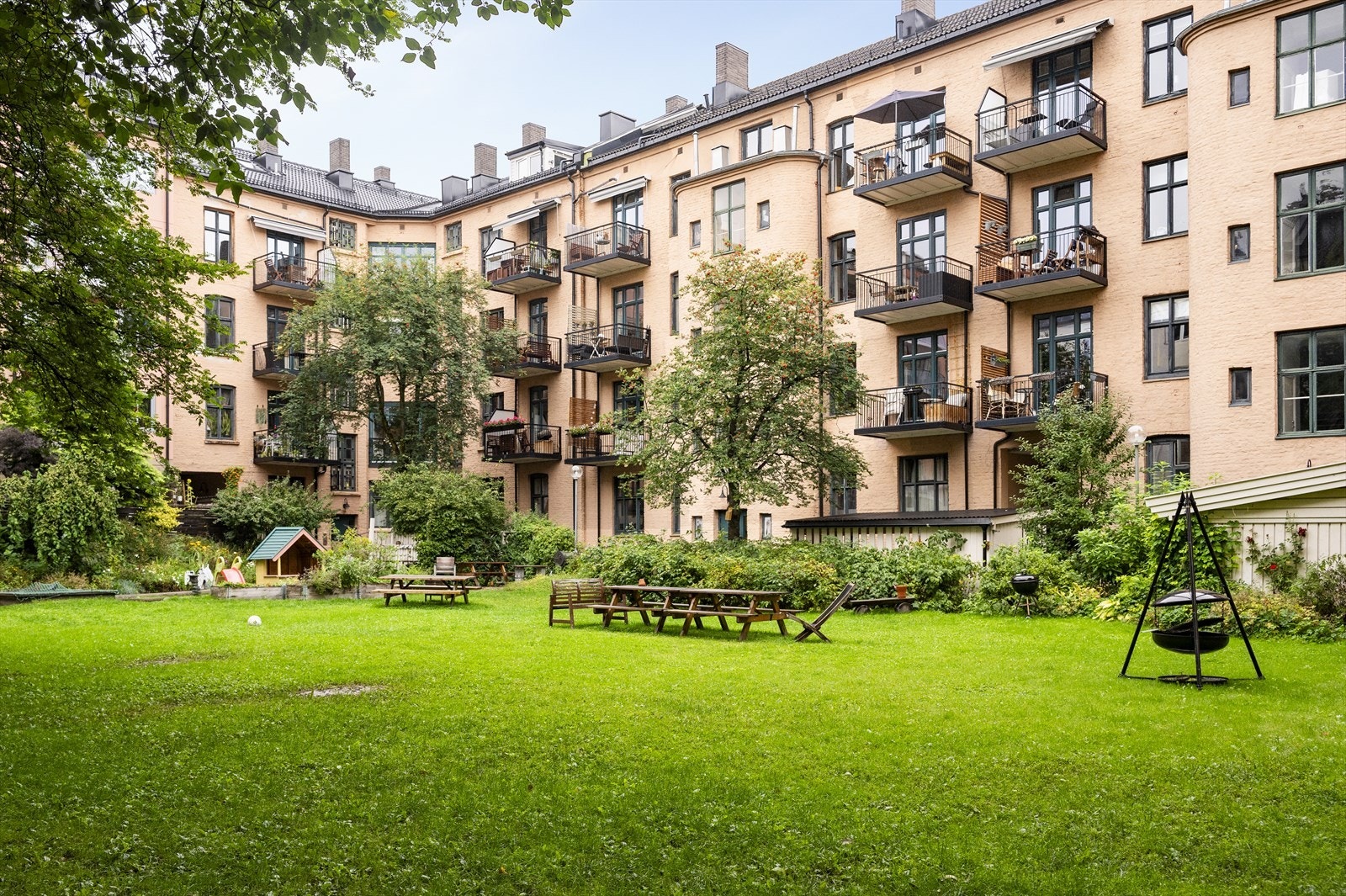 Bakgården er pent opparbeidet med betongheller, gressplen, diverse beplantning samt sittegrupper, lekeapparater og sykkelparkering. Galleribilde