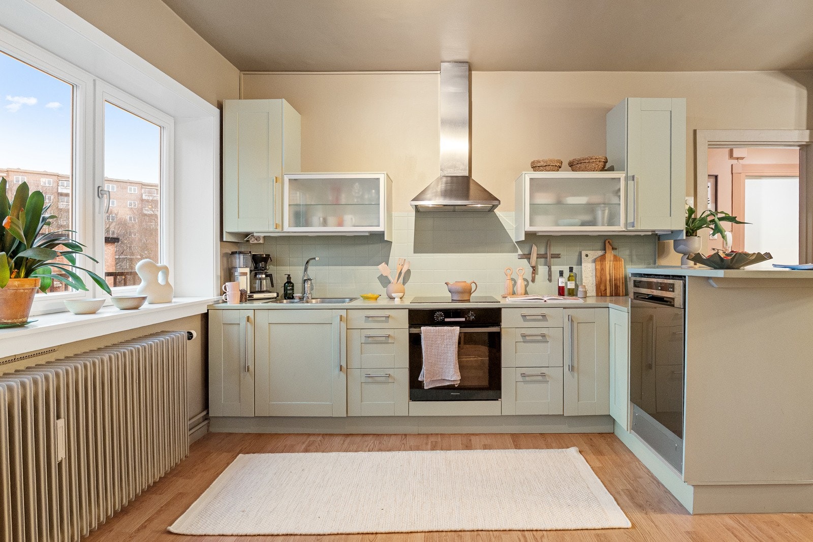 Sjarmerende klassisk kjøkkeninnredning med profilerte fronter og heltre benkeplate malt i lys fargetone med nedfelt kum i rustfritt stål. Galleribilde