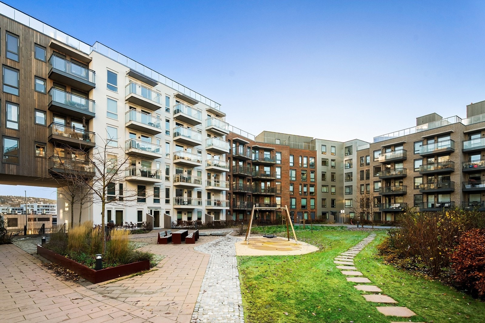 Bakgården er opparbeidet med beplantning, sittegrupper og lekeplass for beboerne i Humla borettslag. Galleribilde